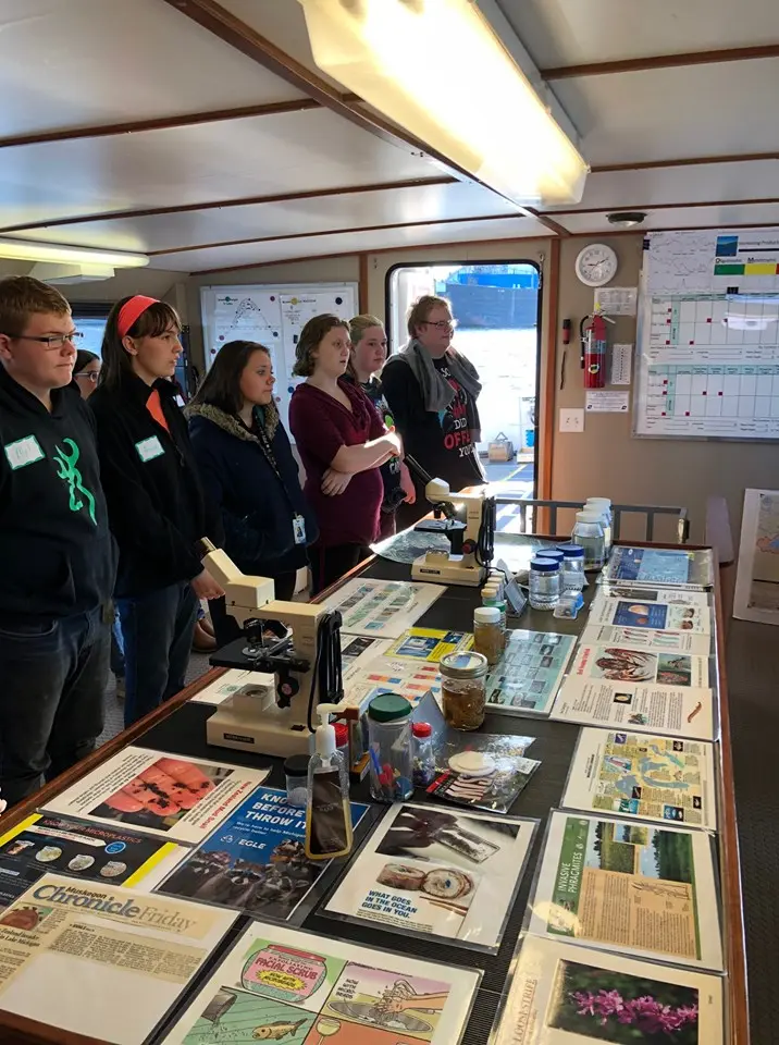 a group of people standing in a room with a table with posters and a microscope