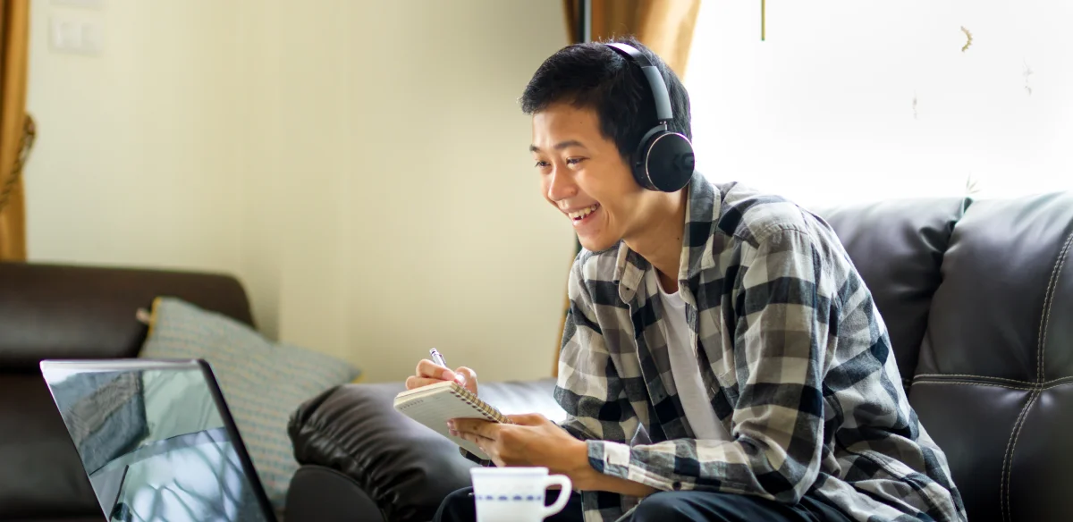 Student taking notes and wearing a headset